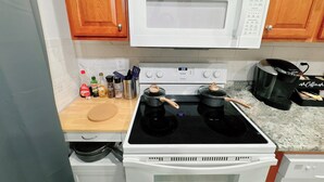 A kitchen with a white GE microwave, a Whirlpool stove, and a Keurig coffee maker. - 115#202 / Charming Downtown Dubuque Apartment (Dubuque)