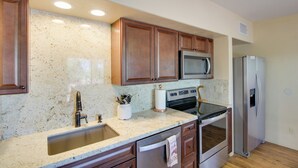 A kitchen with granite countertops, wooden cabinets, stainless steel appliances, and a dishwasher. - Tucson Home - Hiking Trail Access On-Site! (Tucson)