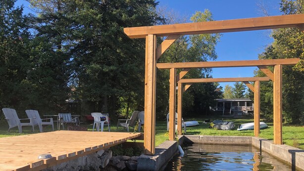 A wooden deck with chairs and a small pond.