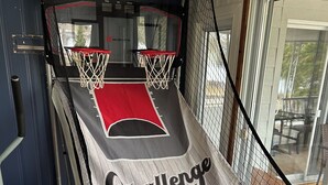A basketball court setup with a hoop, a red mat, and three basketballs.