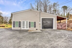 A single-story building with a large garage door, a covered entryway, and a small porch. - Beautiful Renovated Lake Cottage in SW County and only minutes from Downtown! (Roanoke)