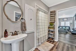 A bathroom with a white sink, a mirror, and a shower curtain. - Beautiful Renovated Lake Cottage in SW County and only minutes from Downtown! (Roanoke)
