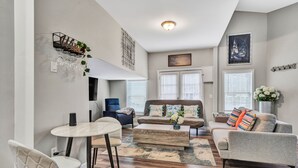 A modern living room with a round coffee table, two sofas, a dining table with chairs, and a bookshelf. - Beautiful Renovated Lake Cottage in SW County and only minutes from Downtown! (Roanoke)