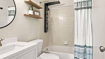 Une salle de bain comprenant des toilettes, un lavabo et un espace douche.