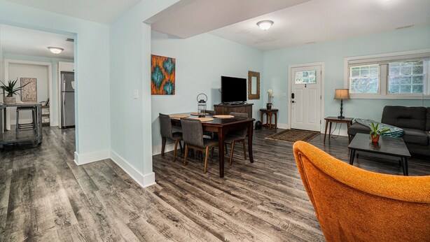 A spacious living area with a dining table, chairs, a sofa, and a TV. - Orchard Beach House Unit #2 (Manistee)