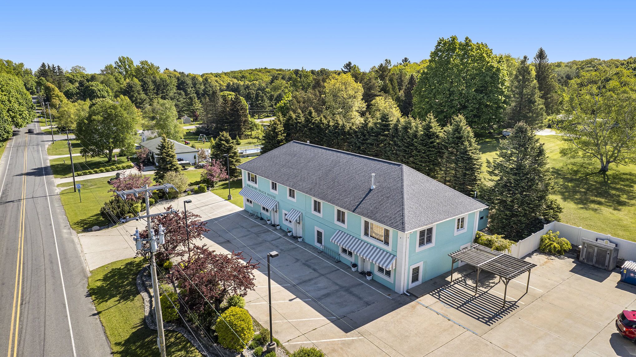 A two-story building with a flat roof, a parking lot, and a road in the background.