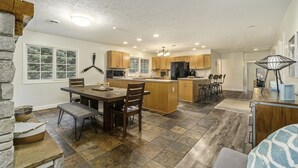 A spacious kitchen with a central island, wooden cabinets, and a dining area with a table and chairs. - Orchard Beach House Unit #4 (Manistee)