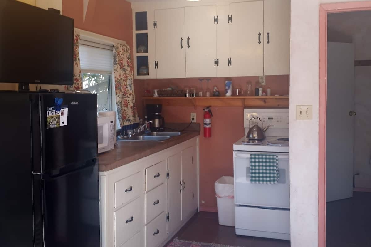 A compact kitchen with a refrigerator, microwave, stove, and cabinets.
