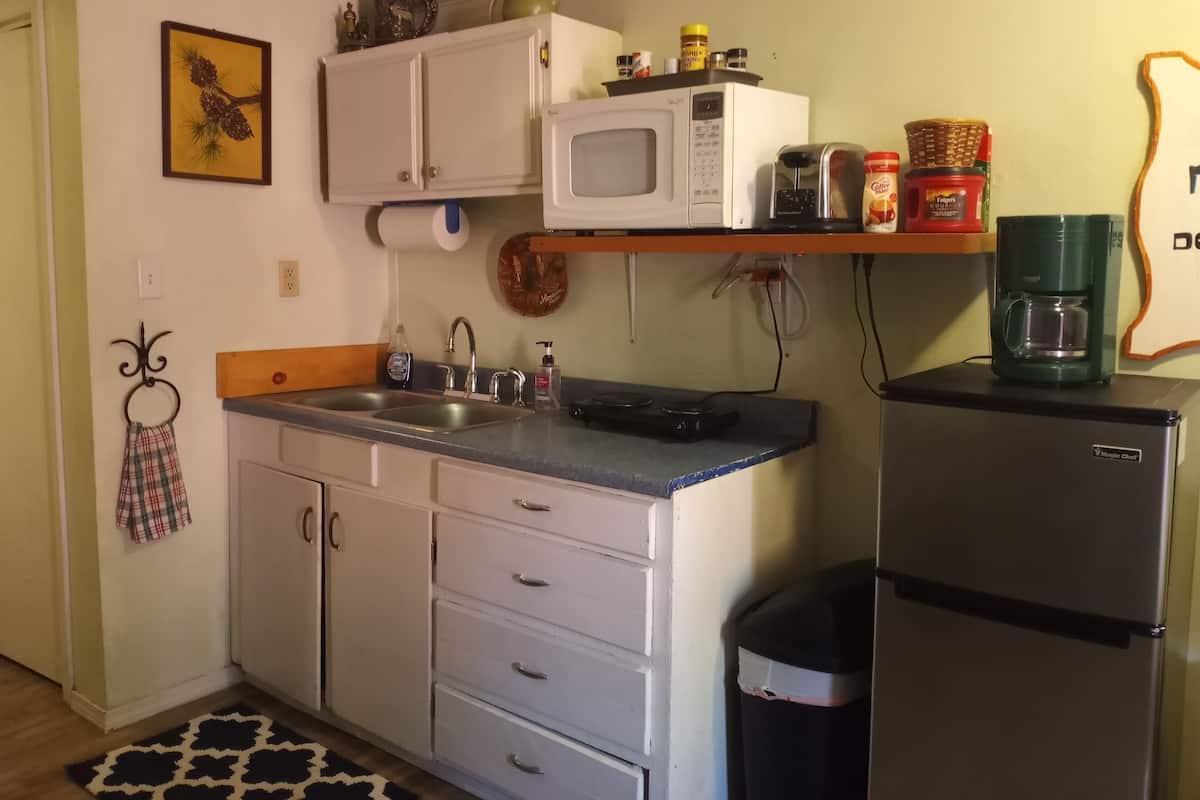 A compact kitchen with a microwave, sink, and a refrigerator.