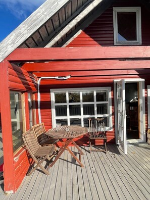 Un bâtiment en bois rouge doté d’un patio couvert comprenant une table et des chaises.