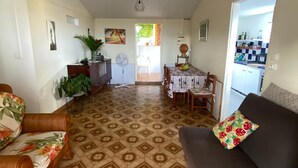 A spacious living area with a patterned floor, a dark sofa, a wooden chair, and a dining table with chairs. - Bright house overlooking the bay of Marin (LE MARIN)