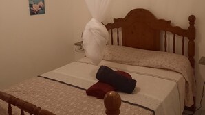 A bedroom with a wooden bed frame, a canopy, and a bedside table. - Bright house overlooking the bay of Marin (LE MARIN)
