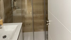 A modern bathroom with a glass shower enclosure, a white sink, and a mirror.