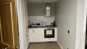 A compact kitchen with white cabinets, a microwave, a stove, and a sink.