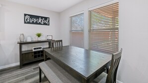 A dining area with a wooden table, benches, a console table with decorative items, and a wall sign that reads "thankful." - Beautiful and Spacious, Home - Great location! (San Antonio)