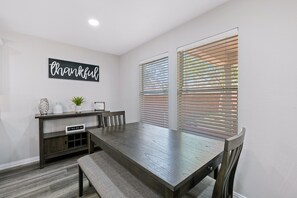 A dining area with a wooden table, benches, a console table with decorative items, and a wall sign that reads "thankful." - Beautiful and Spacious, Home - Great location! (San Antonio)