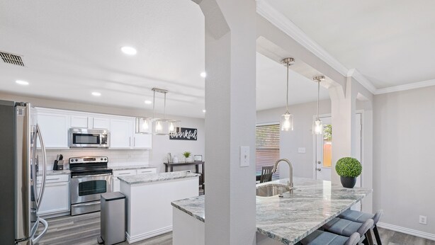 A modern kitchen with white cabinetry, stainless steel appliances, and a marble countertop. - Beautiful and Spacious, Home - Great location! (San Antonio)