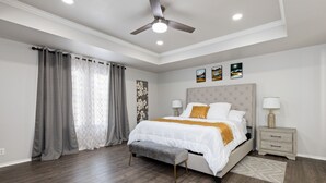 A bedroom with a bed, bedside tables, a ceiling fan, and artwork on the wall. - Beautiful and Spacious, Home - Great location! (San Antonio)