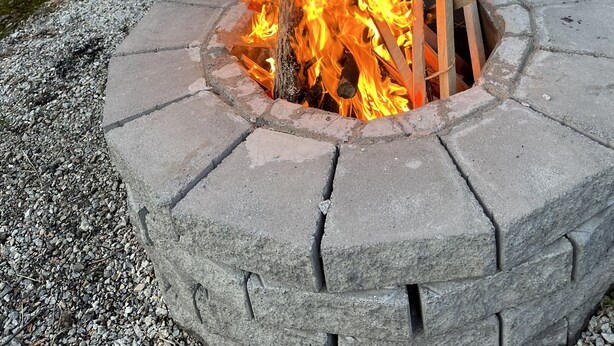 A fire pit with logs, surrounded by a stone wall and a bag nearby. - Warm and inviting, close to the best New England hiking and outdoor fun! (Bartlett)