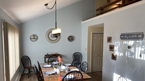 A dining room with a wooden table set for four, black chairs, and a hanging light fixture. - Warm and inviting, close to the best New England hiking and outdoor fun! (Bartlett)