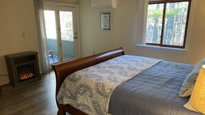 A bedroom with a bed, a fireplace, a window, and a door leading to a balcony. - Warm and inviting, close to the best New England hiking and outdoor fun! (Bartlett)