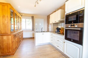 Een moderne keuken met witte kastjes, een houten kast en een inbouwoven.