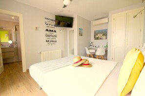 A hotel room with a bed, a desk, and a chair. There is a wall with motivational quotes and a painting.