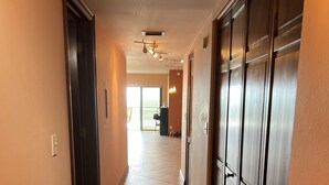 Een hotelhal met een betegelde vloer, houten deuren en een plafond met inbouwverlichting.