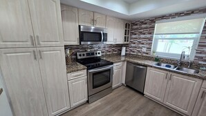 A modern kitchen with light wood cabinets, stainless steel appliances, and a granite countertop. - Luxurious & Spacious Townhouse in Prime Location (Miami)