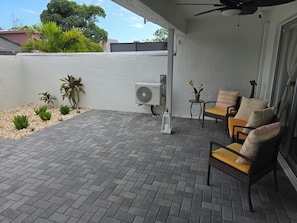 A patio with a ceiling fan, outdoor furniture, and potted plants.