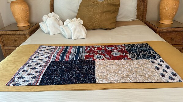 A bed with a quilt featuring a patchwork design, a white pillow, and a brown pillow.