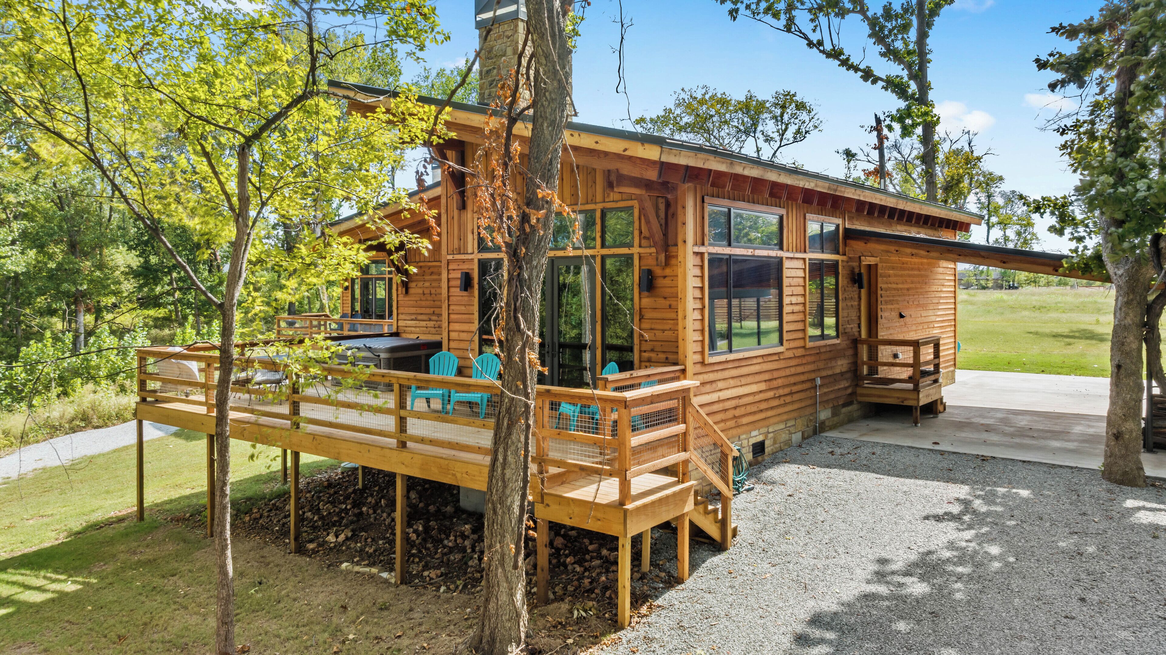 A wooden cabin with a deck, outdoor seating, and a view of the surrounding forest.