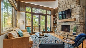 A spacious living room with a stone fireplace, large windows, and a cozy seating area.