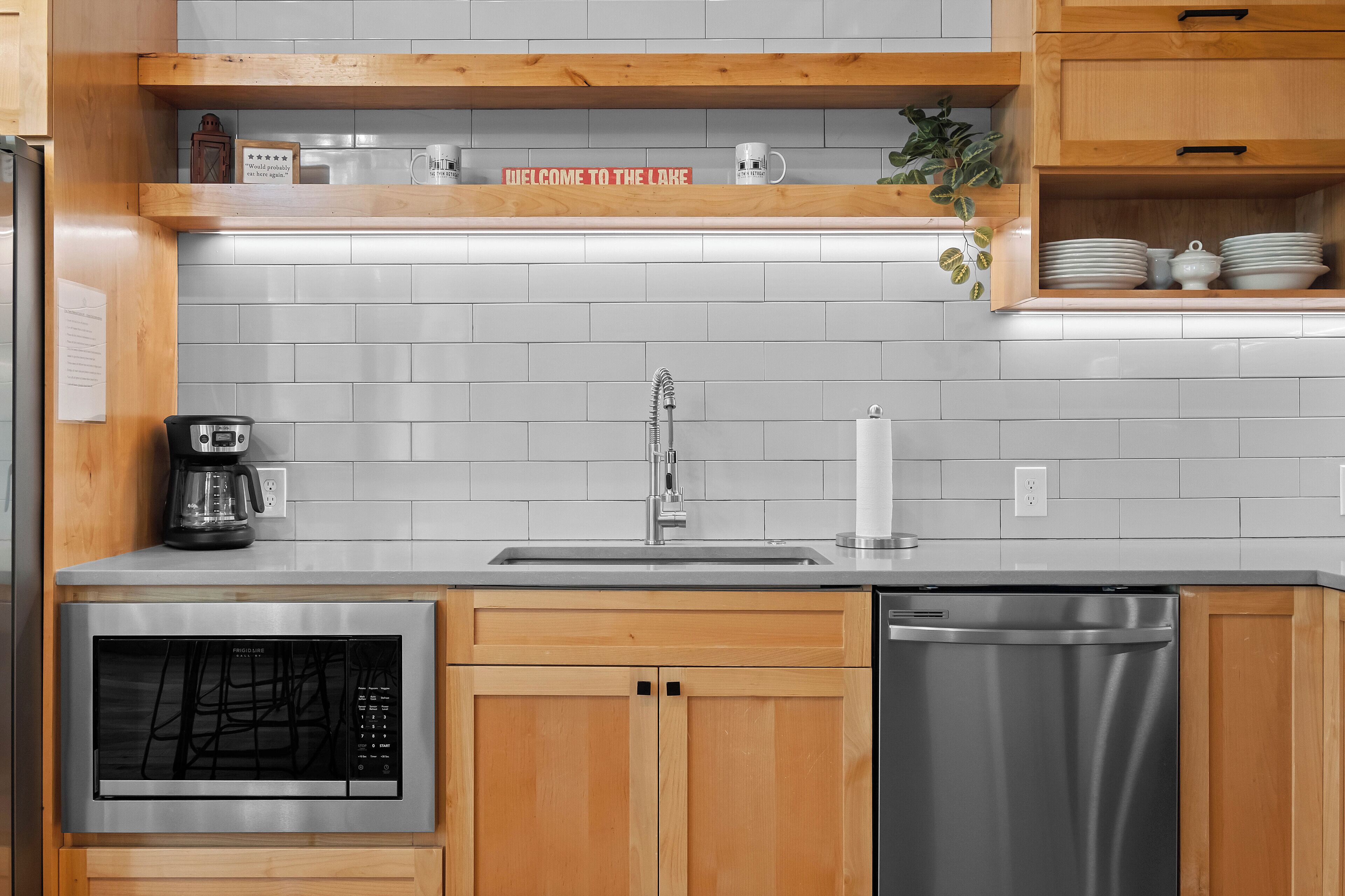 A kitchen with wooden cabinets, a stainless steel dishwasher, a built-in oven, and a coffee maker.
