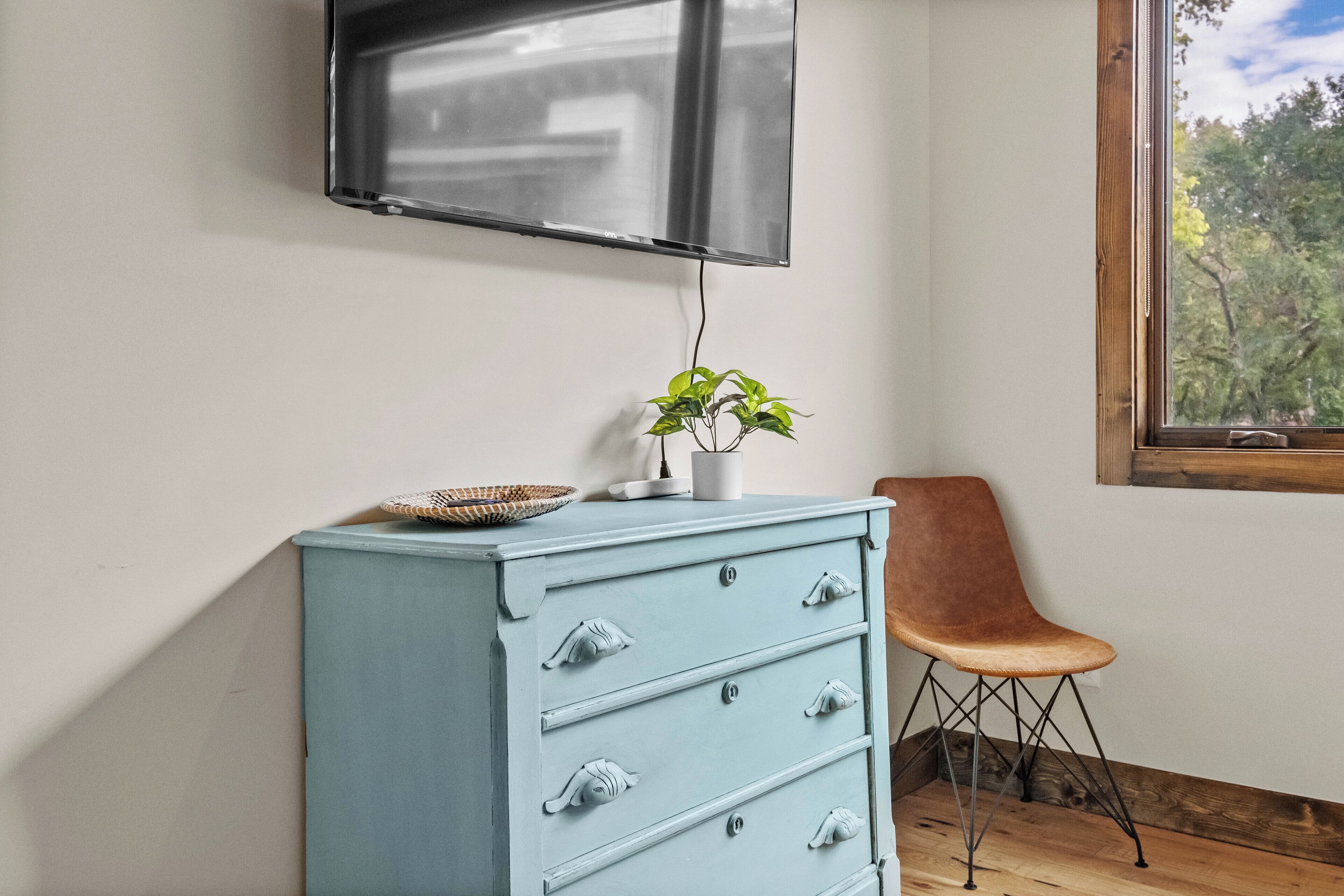 A light blue dresser with drawers, a small plant, and a basket on top.