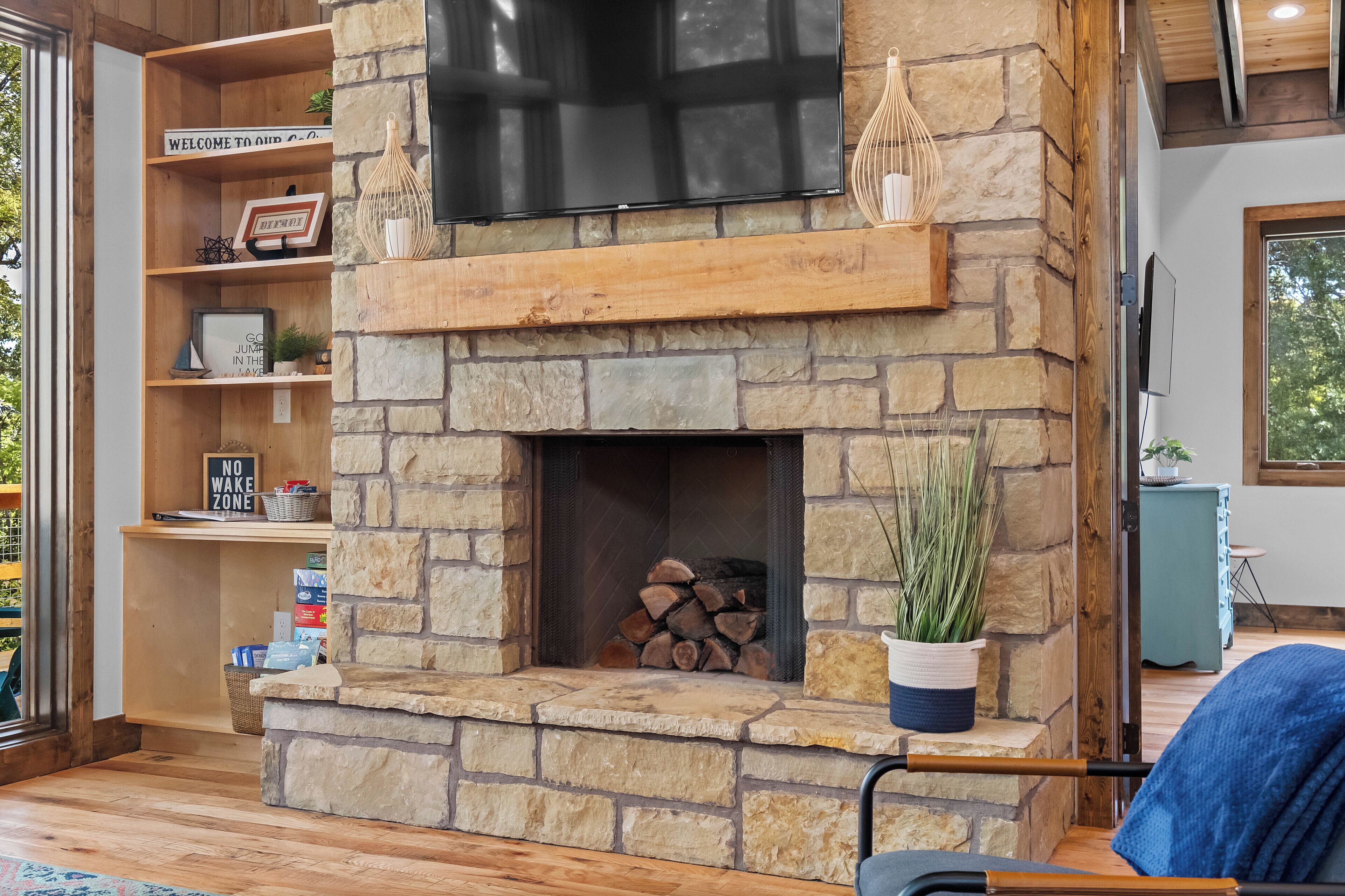 A stone fireplace with a flat-screen TV above, surrounded by shelves with various items.