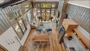 A spacious, open-plan living area with a wooden dining table, seating, and a large window overlooking a garden.
