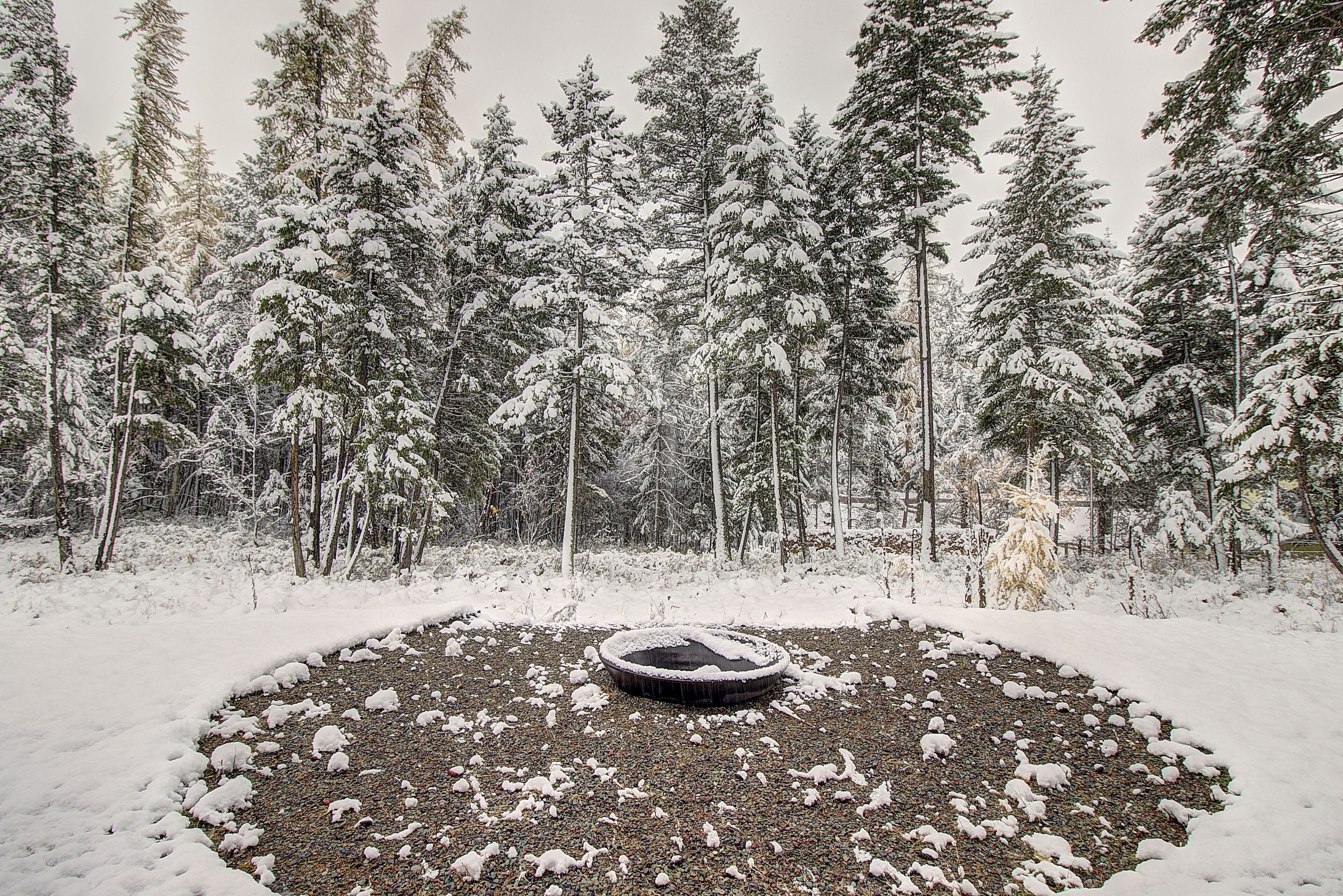 A circular stone structure surrounded by snow-covered ground and trees.