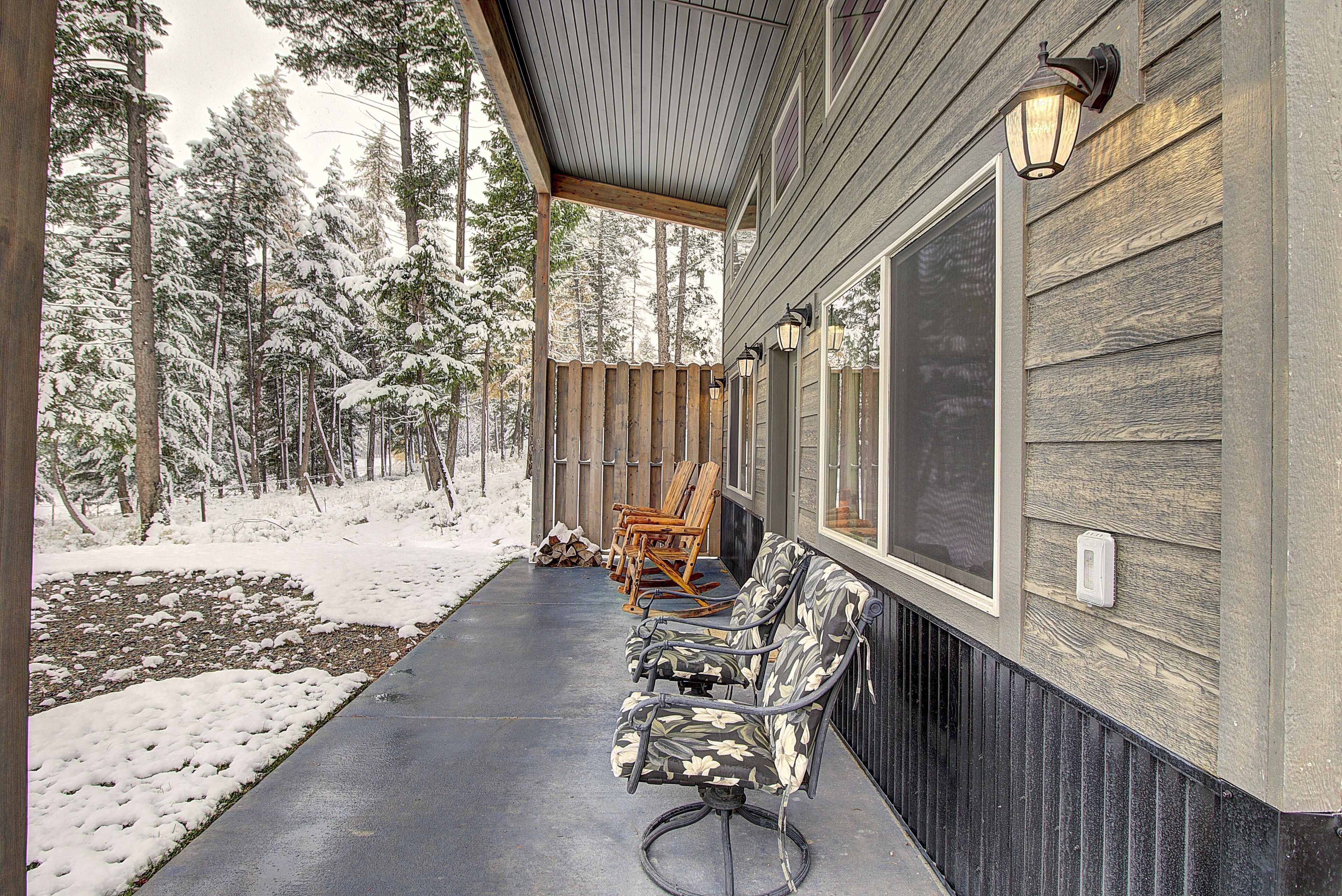 A covered porch with a bench, a wooden fence, and a snow-covered landscape.