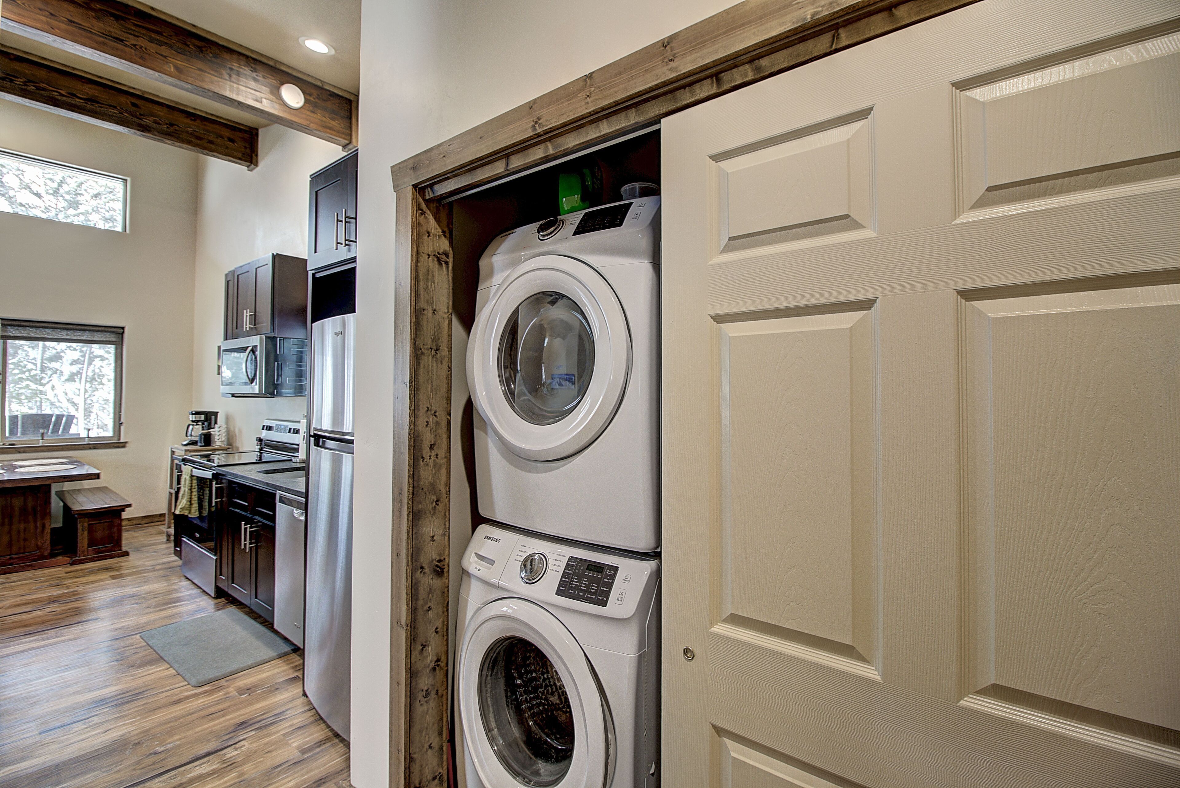 A laundry area with stacked washers and dryers, a microwave, and a sink.