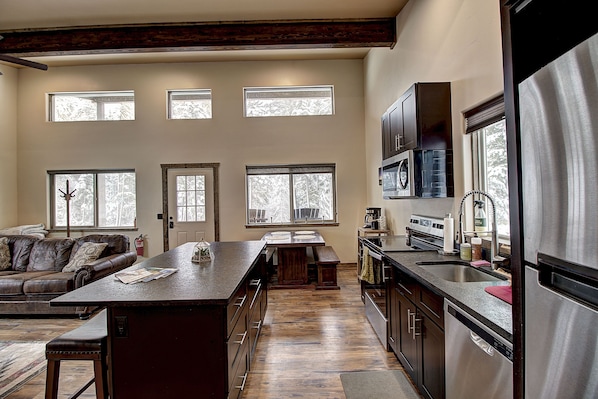 A spacious kitchen with a central island, wooden flooring, and large windows providing natural light. - Spacious 1 Bedroom 1 Bathroom with Sofa Sleeper (Columbia Falls)