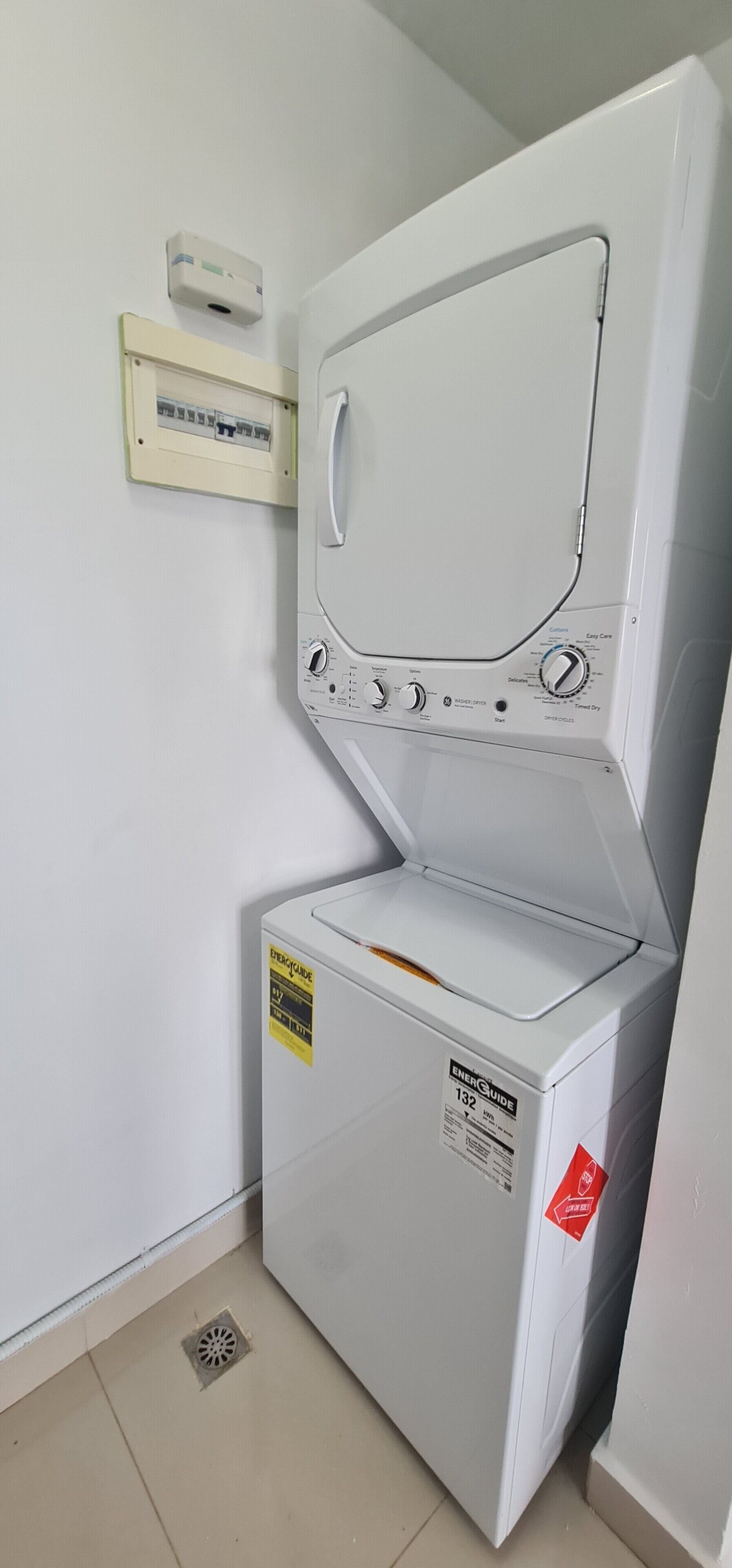A compact, white, front-loading washing machine with a control panel, a power outlet, and a vent.
