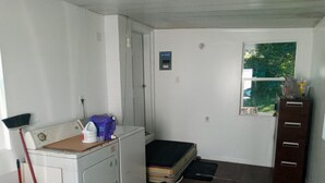 A compact laundry room with a washing machine, a drying rack, and a small storage cabinet.