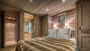 A wooden cabin bedroom with a bed, two bedside lamps, and a framed picture on the wall.