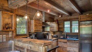 A rustic kitchen with wooden cabinetry, a central island, stainless steel appliances, and pendant lighting.