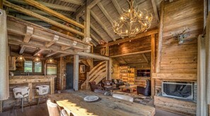 A rustic log cabin interior with a dining area, bar, and fireplace.