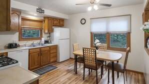 Une cuisine compacte avec des meubles en bois, un lave-vaisselle encastré, une cuisinière et un coin repas comprenant une table et des chaises.