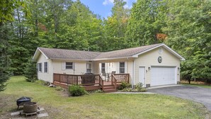 Une maison de plain-pied avec une terrasse à l’avant, un garage et une pelouse bien entretenue.