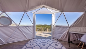Una carpa con un tapete de diseño geométrico, una terraza de madera y una vista despejada del paisaje.