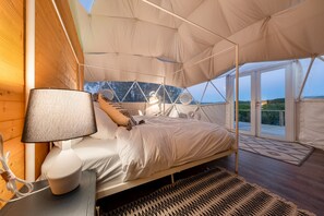 Una tenda-camera con un letto, una lampada e vista sull'esterno.